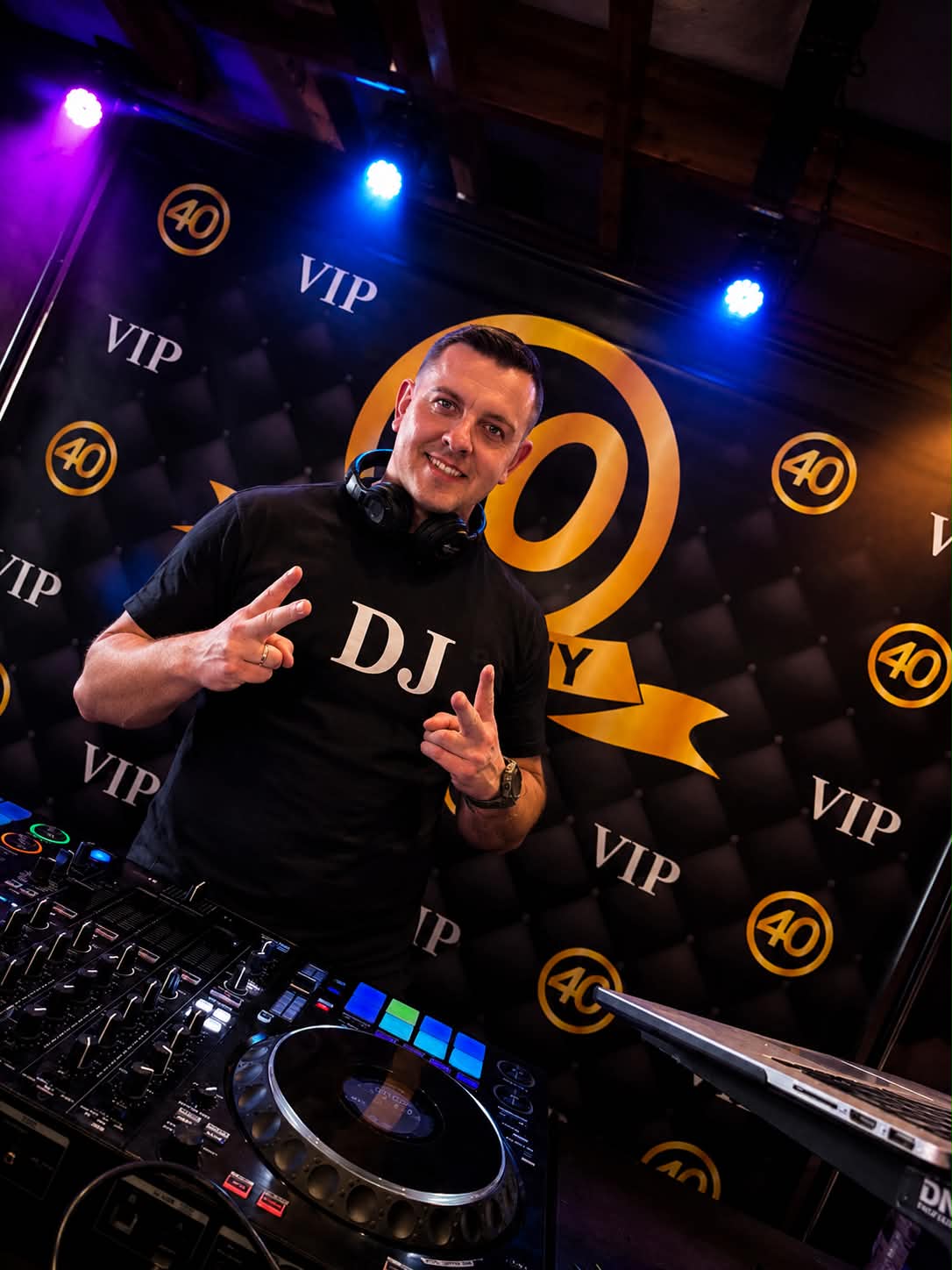 DJ Nevil za konsoletą z oświetleniem scenicznym